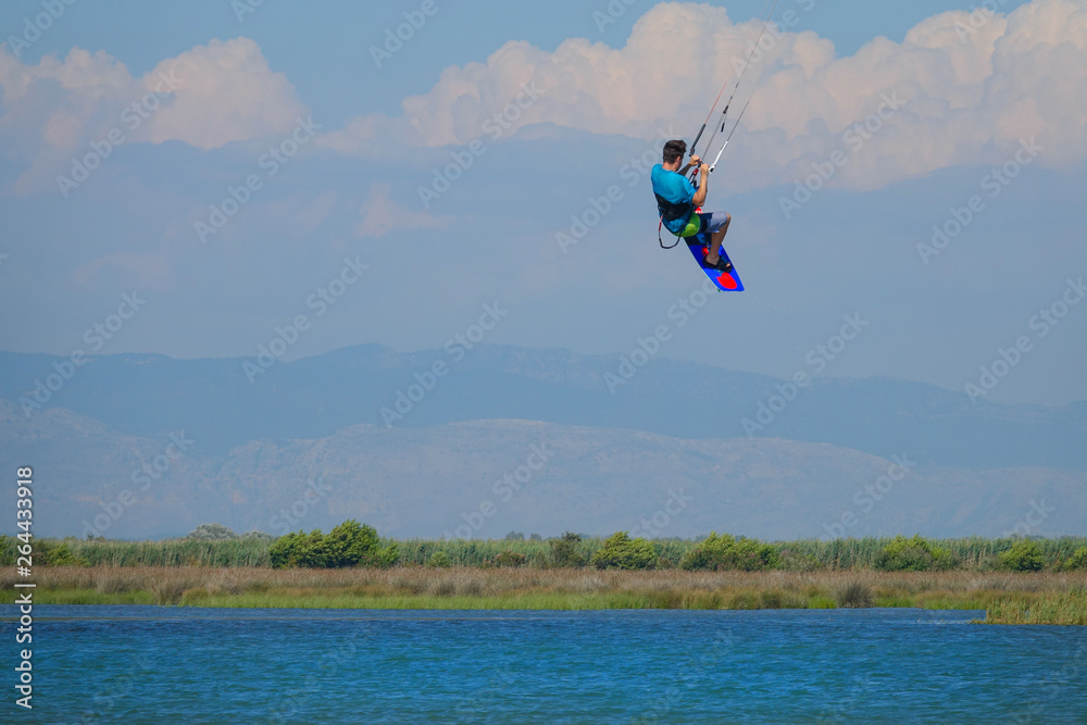 Unrecognizable man jumps in air as he kiteboards along the shoreline of Lefkas. Unrecognizable man jumps in air as he kiteboards along the shoreline of Lefkas.