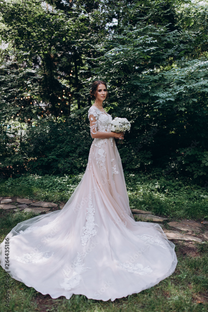 Fototapeta premium A bride in a white dress is holding a beautiful wedding bouquet.