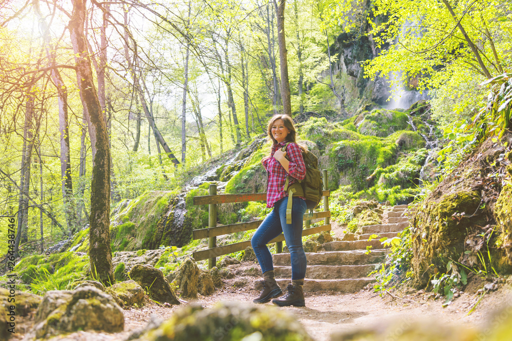 Obraz premium Hiker woman with backpack walking on path in summer forest