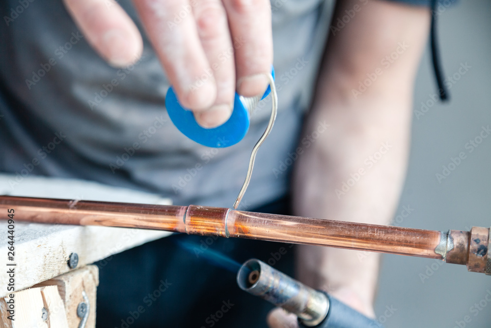 Closeup professional master plumber holding flux paste for soldering
