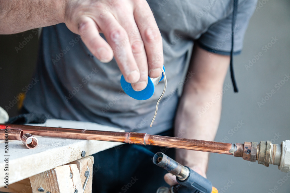 Fotka „Closeup professional master plumber holding flux paste for