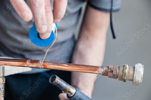 Closeup professional master plumber holding flux paste for soldering and brazing seams of copper pipe gas burner. Concept installation and repair of an apartment building pipeline, leakage