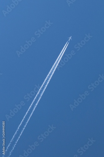 France - Plane flying and leaving a long white trail behind in the blue sky