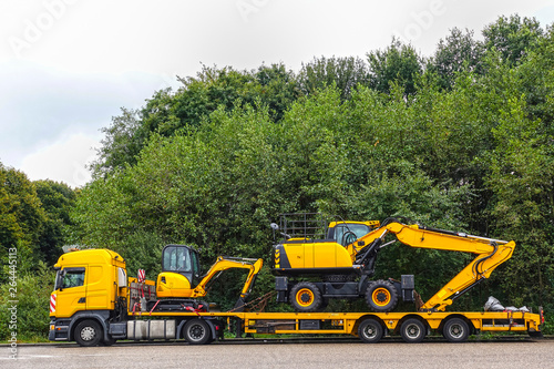 Low loader trailer carrying two excavators parking on a public truck parking area of a truck stop.