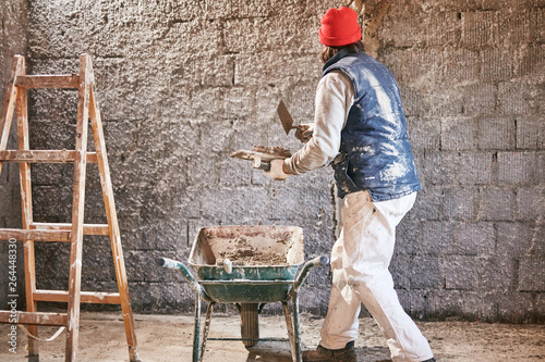 Real construction worker making a wall inside the new house. © astrosystem