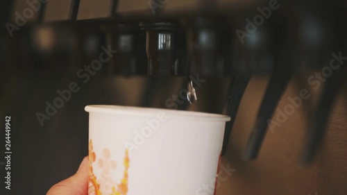 A man pussing the machine with his hand whereof sweet drink flows into the paper glass. photo