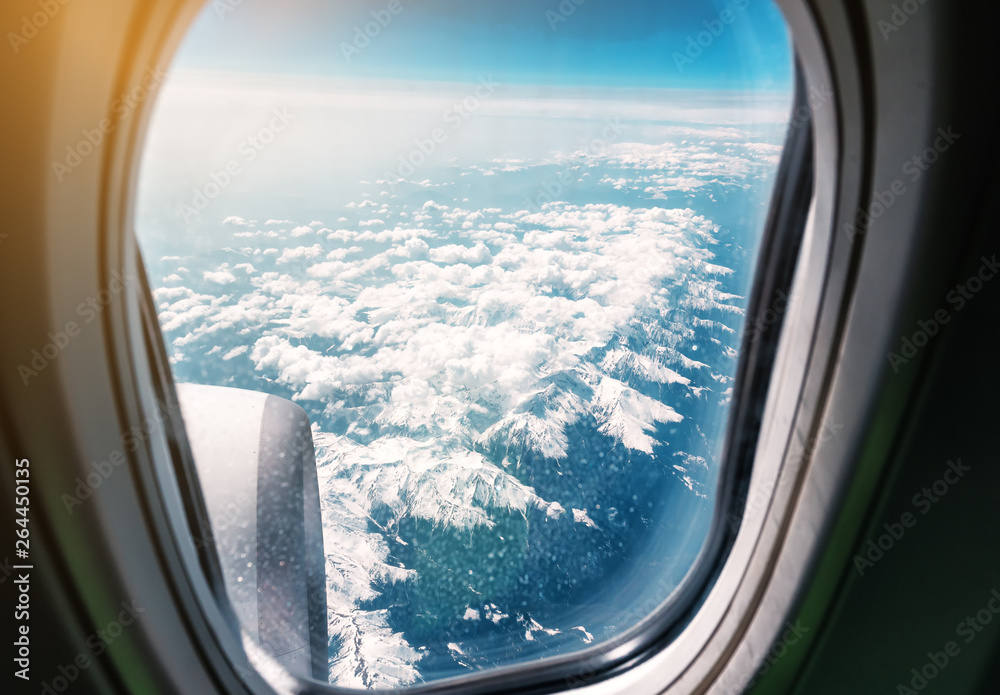 snow-capped mountains through the window of the plane