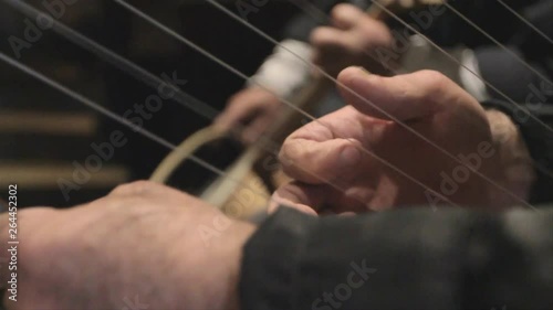 Close up of hands playing a traditional Georgian harp and the chuniri string instrument, with wrack focus on both instruments.