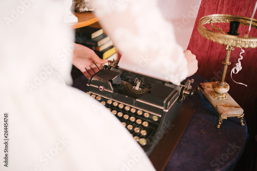 Bride in a white wedding dress works on a typewriter