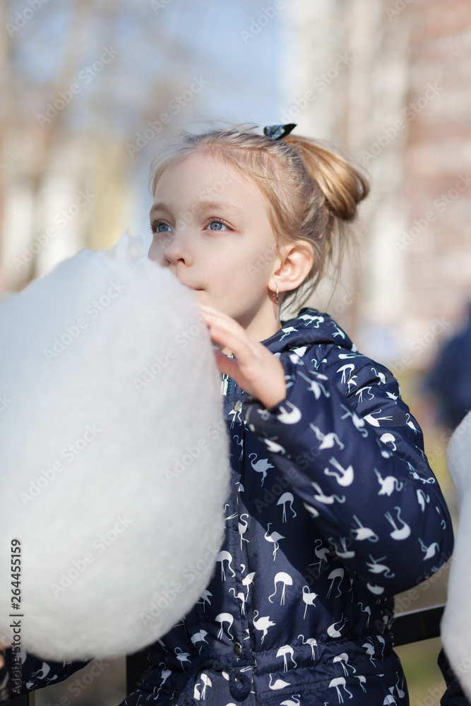 Girl eating cotton candy in a spring park Girl eating cotton candy in a spring park