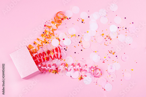 Box on pink background with multicolored serpantine and confetti. photo