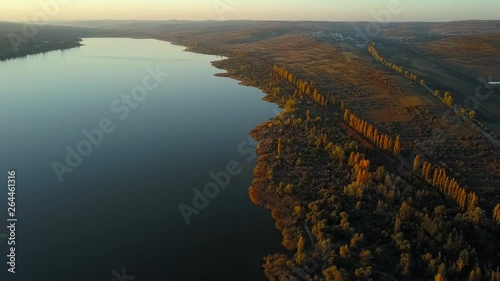 Picteresque birds eye view of Ghidighici lake (the Chisinau Sea) in the golden hour with mirror-like surface and bronze color forests and fields stretching far photo