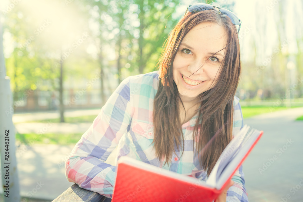 Obraz premium Woman with a book in his hands in the Park. Female, student is reading an interesting book sitting on the bench in the park