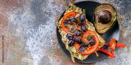 Food banner. Sandwich with tomatoes and mushrooms, basil and avocado on a dark plate. Tasty breakfast.