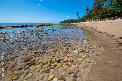 Tropical beach with calm waters with rocks