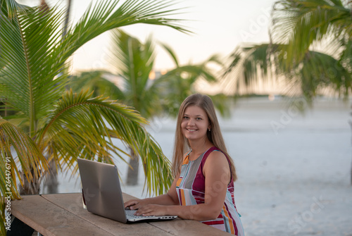 Young woman with computer in front of the palm