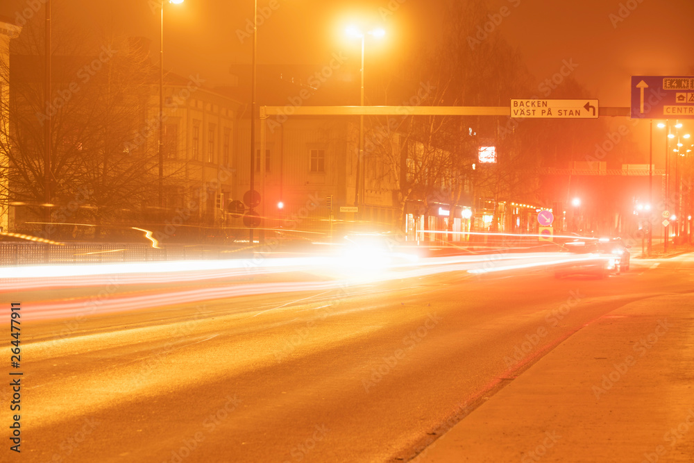 colorful light traces from busy night traffic on the Umea city street, foggy autumn weather, Sweden