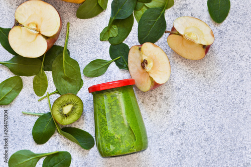 Green smoothie with banana, kiwi, apple and spinach on a concrete background. Detox menu.