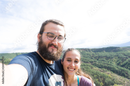 Young Happy hiker couple taking a selfie in the mountain with a smart phone
