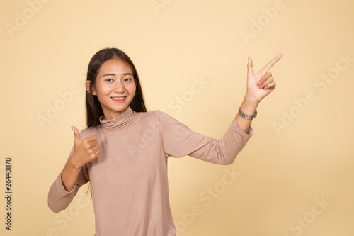 Young Asian woman point and thumbs up.