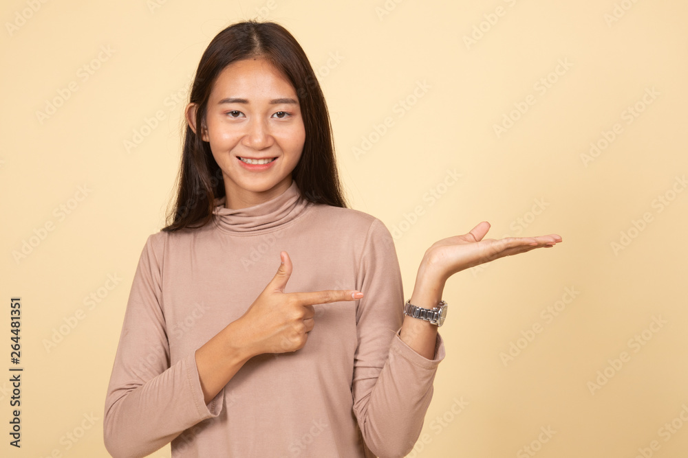 Beautiful young Asian woman point to palm hand.