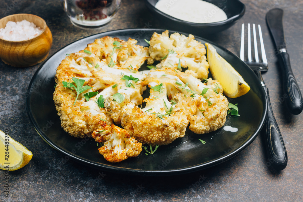 Fried cauliflower steak with greens and spices on dark background. Fried cauliflower steak with greens and spices on dark background.
