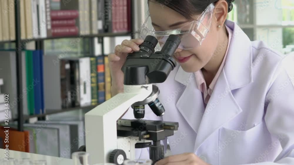 Scientist woman is looking through microscope in modern laboratory or medical center. Concept of science, testing development and lab industry. Scientist woman is looking through microscope in modern laboratory or medical center. Concept of science, testing development and lab industry.
