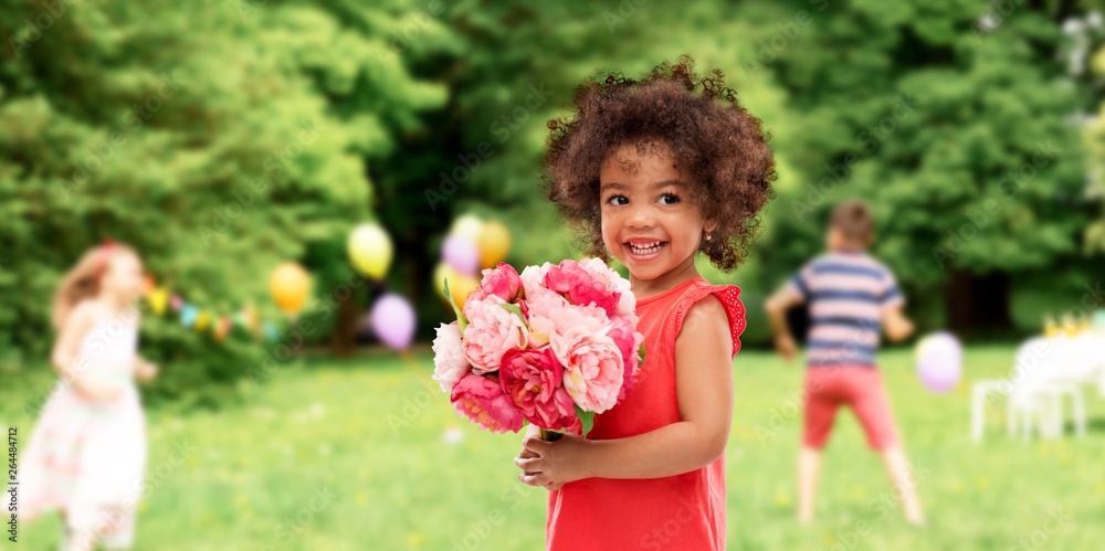 childhood and people concept - happy little african american girl with flowers at birthday party over summer park background