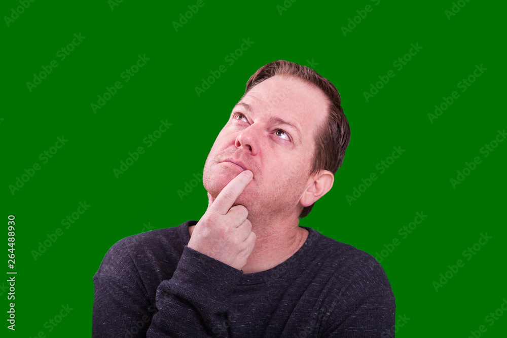 Red headed adult man finger on face looking up in deep thought on green screen backdrop Red headed adult man finger on face looking up in deep thought on green screen backdrop