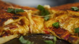 Freshly made hot appetizing peperoni pizza with melted cheese on a wooden table decorating with basil greens by hands of man or woman chef in slow motion close up front view 4K video