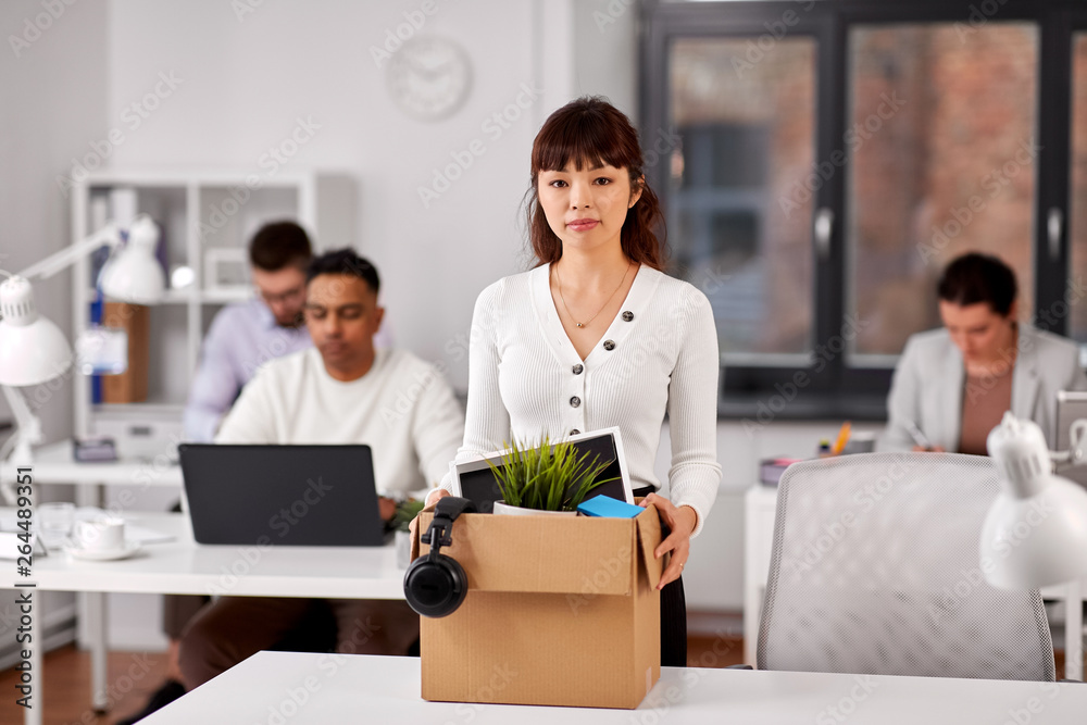 business, firing and job loss concept - sad fired asian female office worker with box of her personal stuff