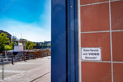 Sign reading "this area is under video surveillance" in german language on a river bank in Berlin
