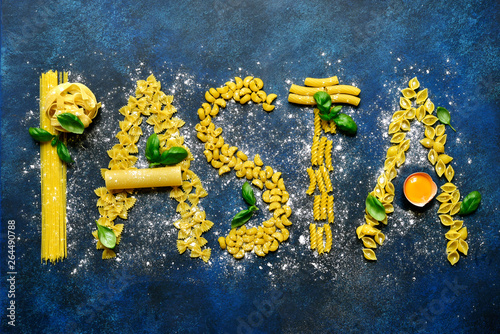 Culinary background with  inscription  made from different types of pasta ( spaghetti, tagliatelle, fusilli, farfalle, canneloni ) and ingredients for making.Top view. photo