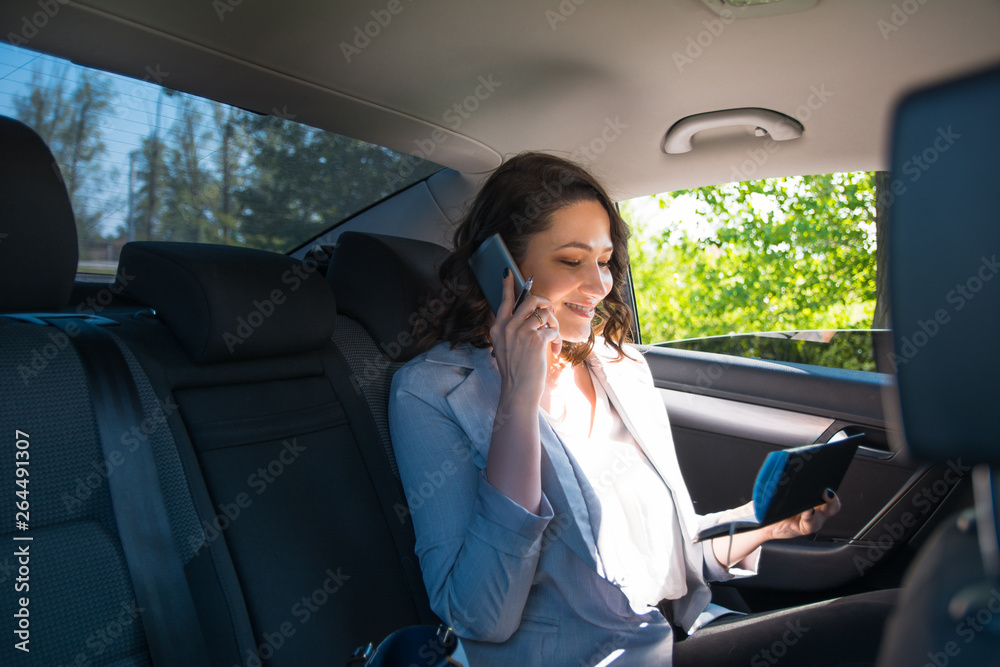 Businesswoman taking notes while sitting on back seat of the car
