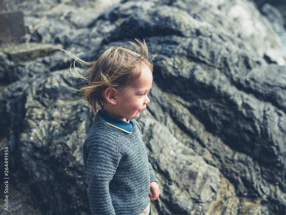 Little toddler standing by some rocks on the coast Little toddler standing by some rocks on the coast