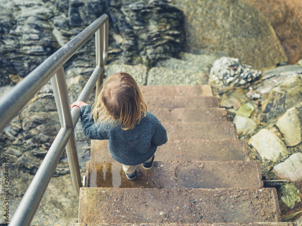 Little toddler going down some stairs on the coast Little toddler going down some stairs on the coast