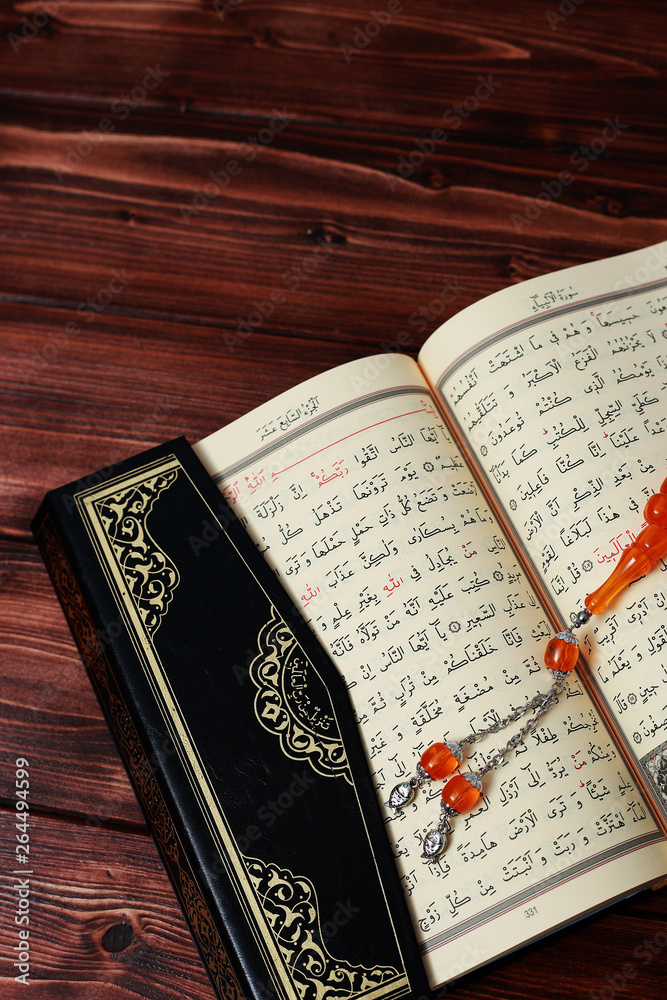 Obraz premium Islamic Holy Book Quran with rosary beads on wooden table background. Kuran the holy book os Muslims. Ramadan concept.