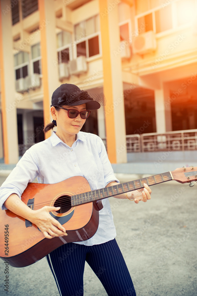 Fototapeta premium woman playing acoustic guitar on street side