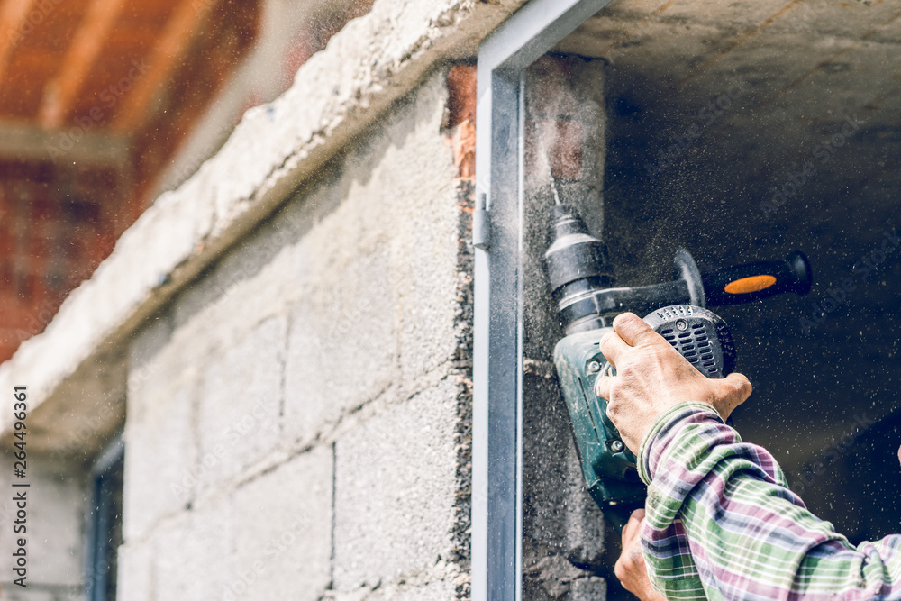 Fototapeta premium Construction industry worker using pneumatic hammer drill to cut the wall concrete brick drilling holes, close up