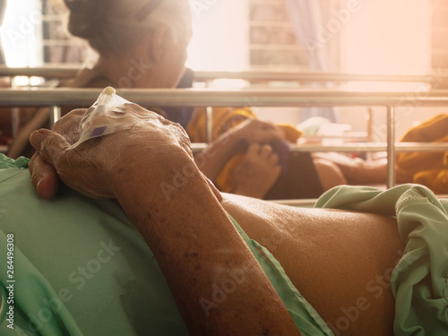 hand of elderly patient with intravenous catheter for injection plug in hand during lying in hospital ward room photo