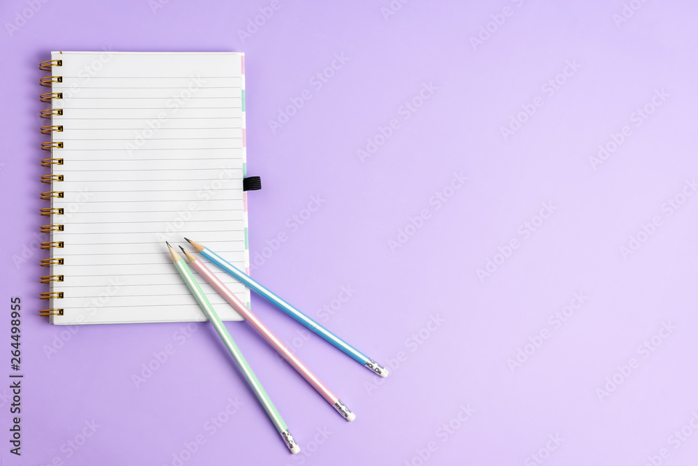 Top view of blank notebook with pencils on purple pastel background, copy space