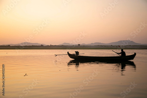 Silhouette fisherman wood boat with sunset in the lake