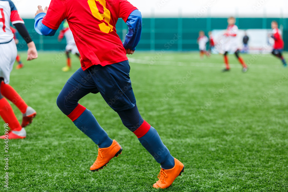 Boys kick soccer ball. Footballers run after the ball on green grass. Kids in white and red shirts dribbling, improve skills. Training, football, hobby, active lifestyle Boys kick soccer ball. Footballers run after the ball on green grass. Kids in white and red shirts dribbling, improve skills. Training, football, hobby, active lifestyle