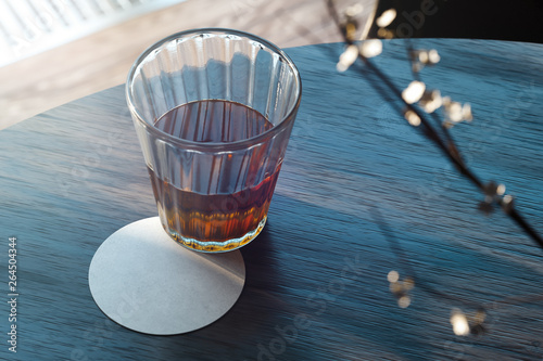 Transparent glass with tea and beer coaster on wooden table. 3d rendering. photo
