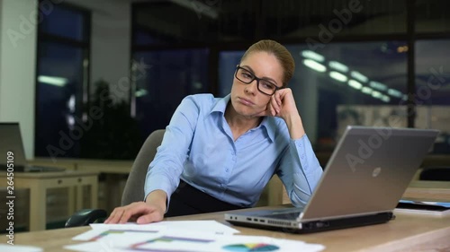 Woman sitting upset hating job while working night shift in office, overtime