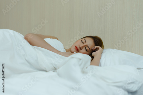 Young beautiful woman sleeps and fully resting on the white background bed. Sexy beautiful woman falls asleep in the bed