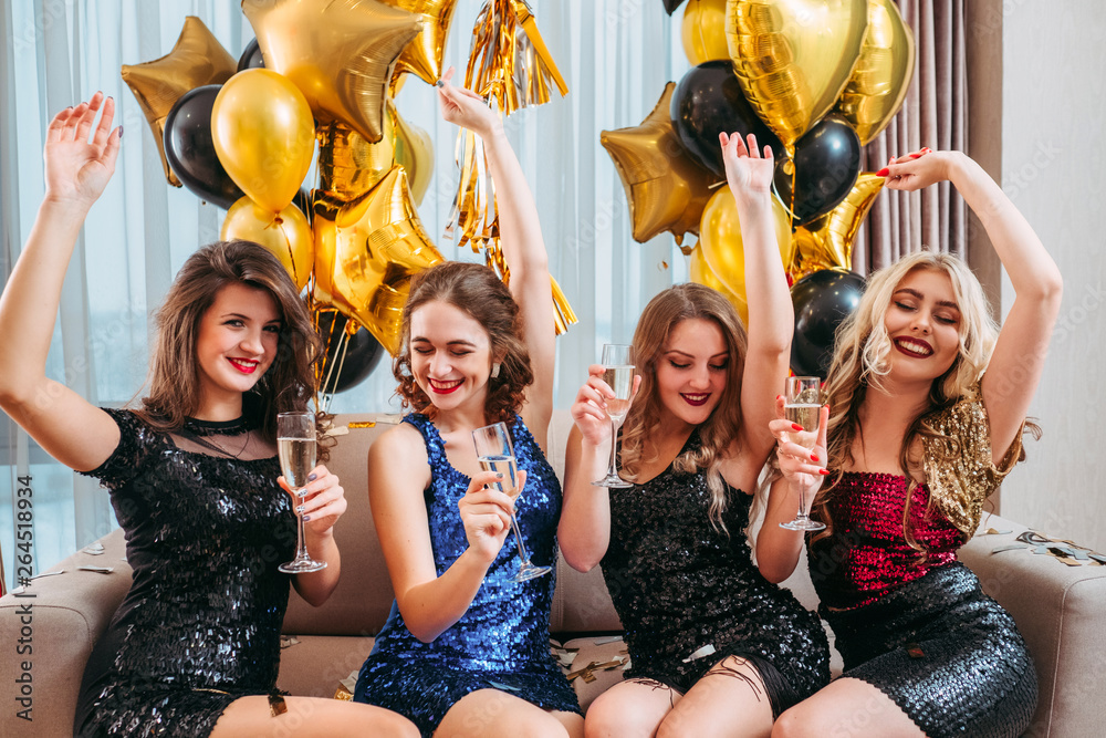 Girls party. Ladies hanging out, enjoying time together, having fun sitting  on sofa, dancing, holding glasses with champagne. Stock Photo | Adobe Stock