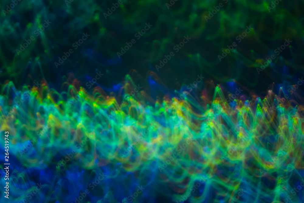 Blurred blue green lines on dark background. Neon lights in motion. Lens flare glow.