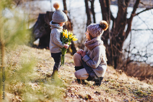 A boy and a girl  having fun outside in early spring in the forest near the water. A sister and brothe together. Friendship and  family concept photo