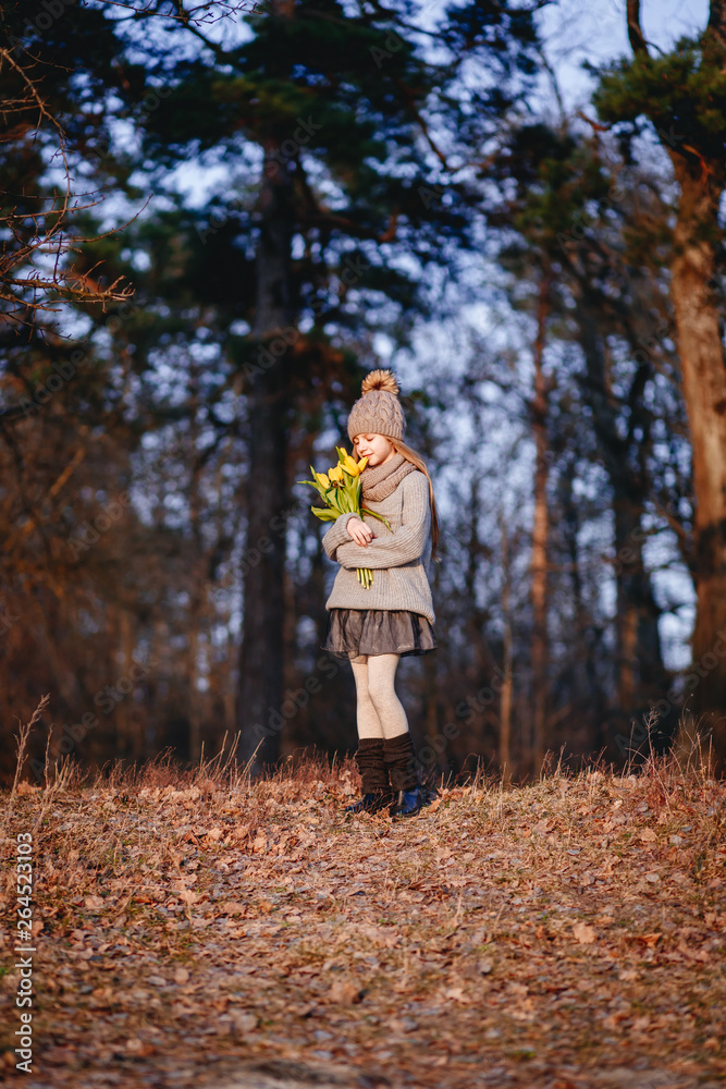 A girl with yellow tulips in early spring on a cold windi evening near the river A girl with yellow tulips in early spring on a cold windi evening near the river